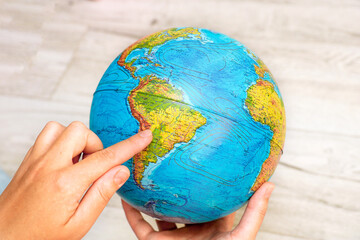 female hand show South America on the globe