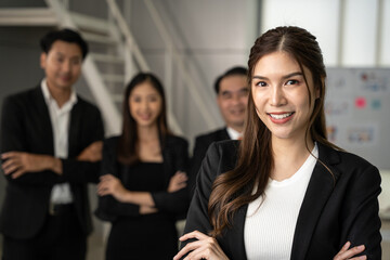 Portrait of young beautiful woman looking to camera in meeting room. She looking to camera with happy expression in her office with team. Business people concept.