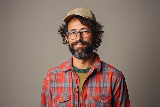 Portrait of a hipster man with glasses and cap over grey background