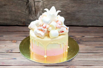 Tender pink birthday cake with melted white chocolate, fondant crown, meringues and marshmallows on...