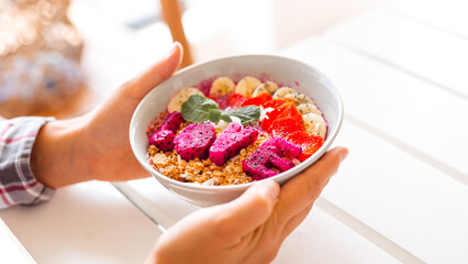 Female hands holding plate with smoothie bowl. The concept of a delicious and healthy breakfast....