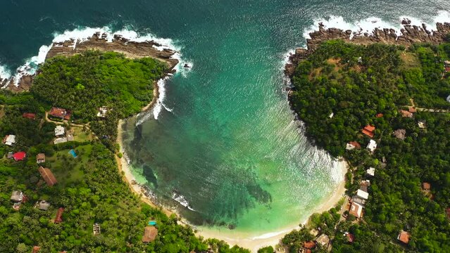 A tropical beach with palm trees and a blue ocean. Hiriketiya, Sri Lanka.