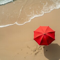Red beach umbrella casting a shadow on sandy beach with approaching waves