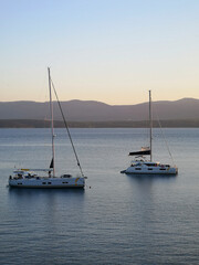 Two sailing boats are anchored in the bay at Zlatni Rat. Soft evening light shortly before sunset. The island of Hvar can be seen in the background.