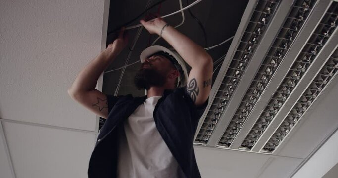 Man, electrician and light installation or wires for maintenance, safety protocol or infrastructure. Male person, ladder and property roof inspection for office upgrade development, project or repair