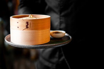 waiter hold Dim sum set mix on bamboo steamer