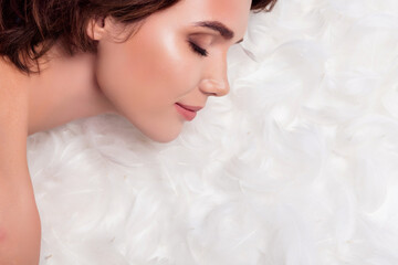 Closeup photo of relaxed young girlfriend sleeping bare closed eyes chilling on white feathers...