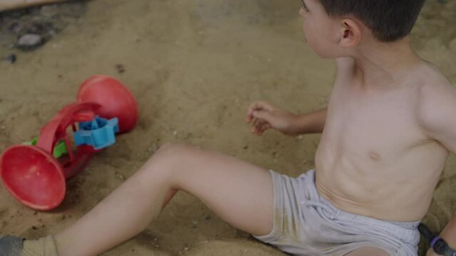 Boy child playing in sandbox. Recreation on playground.