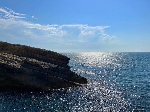Rocks in the sea blue glittering water against sky.