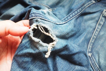 Hand touching ripped dark blue jeans cracked with hole at the crotch near back pocket Need to...