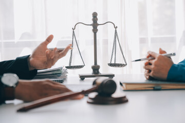 Justice and Law concept. Legal counsel presents to the client a signed contract with gavel and legal law or legal having team meeting at law firm in background
