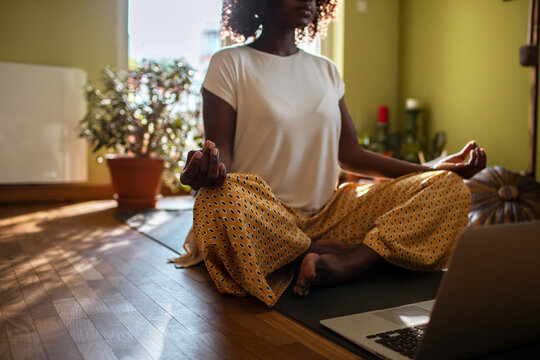 Young african american woman doing yoga and meditating at home