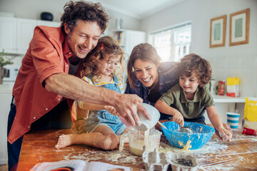 Family baking together in kitchen, kids and parents making cookies