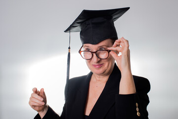 Mature woman with graduation cap looking over her glasses