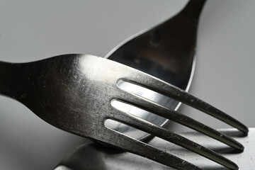 close-up fork and knife placed on a plate on white background