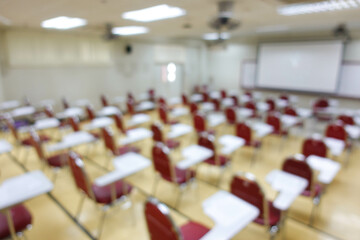 Blurred abstract background of examination room with undergraduate students inside. Blurred view of a student doing the final test in the exam room. Blurry view of study chairs in university.