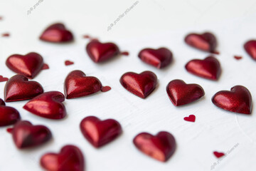 Sparse red hearts confettis on a white surface.
