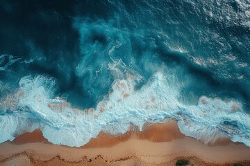 Obraz premium Aerial shot capturing the dynamic interaction between ocean waves and a sandy shoreline, featuring vibrant hues and textures