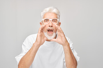 Portrait of senior man in white shouting loudly with hands, news, palms folded like megaphone...