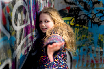teenage girl against the background of a wall with graffiti by unknown authors on the street