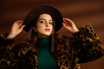 Fashionable confident woman wearing hat, trendy faux fur leopard print coat, green turtleneck,...