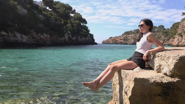 young woman relaxing and sunbathing in crystalline water, full view