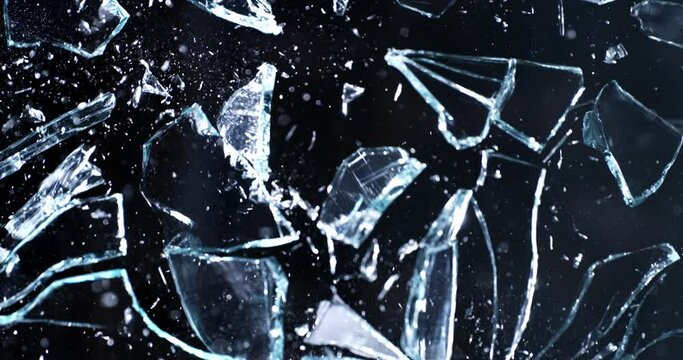 Super slow motion macro of window crystal glass panel is broken shattering in explosion with flying pieces isolated on black background at 1000 fps.