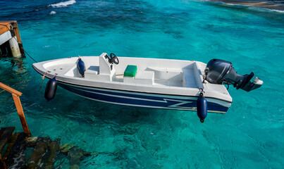 A white boat with a black engine tied up at pier.