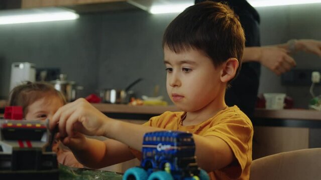 Adorable child playing with car toys on table, boy playing with vehicles at home. Kids toys and entertainment concept