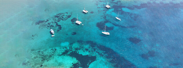 Fototapeta na wymiar Aerial drone ultra wide photo of sail boat anchored in tropical exotic turquoise calm waters forming a blue lagoon