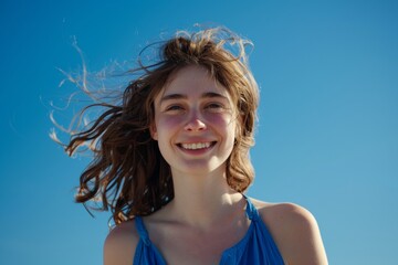 Young Woman Smiling Her Hair is Blown by the Wind - Blue Background Seeing The Upper Body when wearing Blue Clothes in Summer and The Sun is Bright Wallpaper created with Generative AI Technology