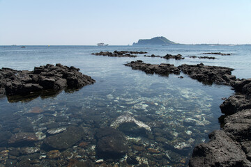 Fototapeta na wymiar The beach of black rocks at the island seaside