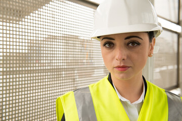Young woman working in the engineering industry, wearing white safety helmet and high visibility vest.
