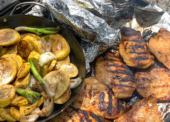A loaded, outdoor grill full of chicken, squash, and corn on the cob
