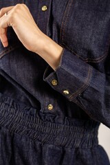 Blue denim shirt with gold buttons on a white background