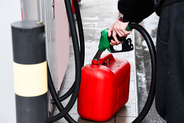 A man pouring fuel into a canister at a gas station.