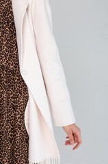 Fashionable model in warm winter coat and leopard dress posing in studio