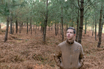 Portrait of young man standing with fur jacket in forest