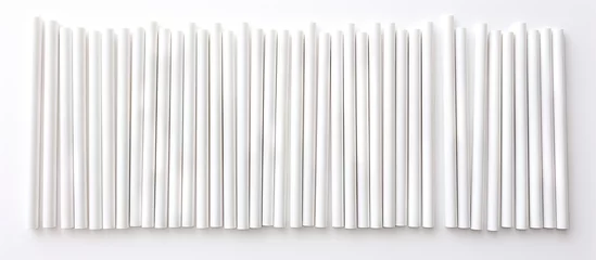 Foto op Plexiglas A cluster of white biodegradable eco-friendly paper drinking straws arranged neatly on a tabletop surface. The straws are resting still and untouched. © Ilgun