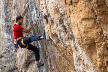Obraz premium Man in red t-shirt scalded on gray wall, playing sports, reaching limit