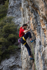 Obraz premium Man in red t-shirt scalded on gray wall, playing sports, reaching limit