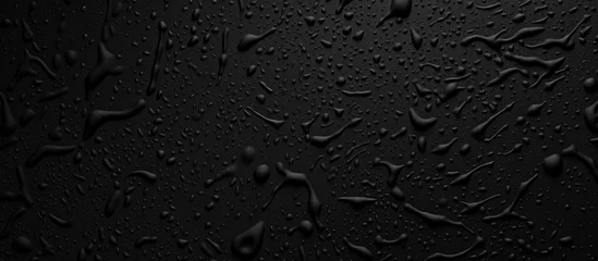 Fotobehang Numerous water drops are scattered across a black, plastic grainy abstract background. The drops reflect light, creating a striking contrast against the dark surface. © Ilgun