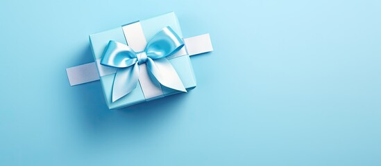 A luxurious blue gift box with a matching bow placed on a blue background. The high angle view showcases the monochrome close-up of this elegant item, perfect for occasions like Fathers Day,