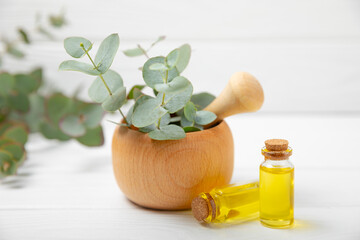 Eucalyptus leaves and mortar on a wooden background.Spa concept.Ingredients for alternative medicine and natural cosmetics. A bottle of essential oil and a bunch of eucalyptus. Organic skin care 