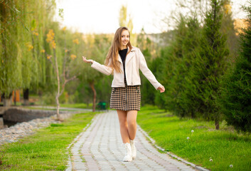 A young smiling girl walking in an autumn park in a good mood. Teenage girl, portrait against a background of nature. Fashion style trend.