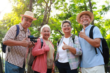 Portrait of a group of Asian elderly people traveling in a natural forest. They give thumbs up,...