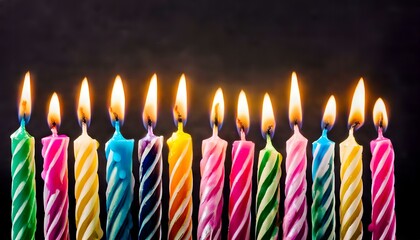 lit multicolored birthday candles with melting wax on black background. birthday celebration card macro photography. copy text space