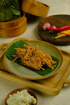 A plate of Tempoyak Ikan Teri or Otun on brown background. Anchovy fish with tempoyak, chili, onion and turmeric. Tempoyak made from fermented durian fruit. Makanan tradisional