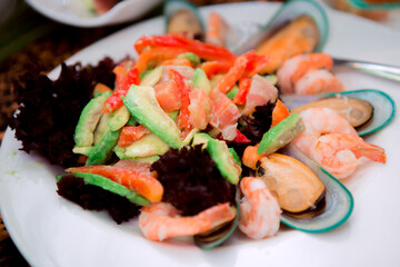Seafood salad with shrimps mussels squid and vegetables on white plate