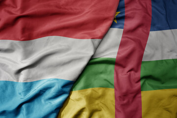 big waving national colorful flag of central african republic and national flag of luxembourg .